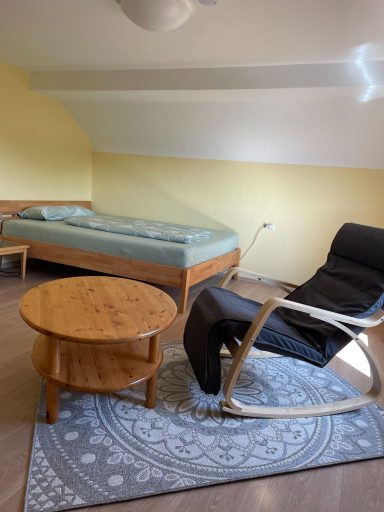Kleines Schlafzimmer im Dachgeschoss mit Bett und Schaukelstuhl